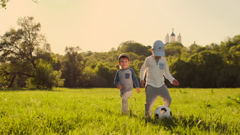Two-small-children-playing-with-a-soccer-ball-laughing-and-smiling-at-sunset.